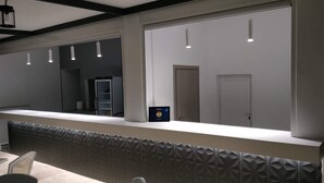 Un comptoir d’accueil moderne agrémenté d’un mur aux motifs géométriques, d’un grand miroir et de luminaires suspendus.