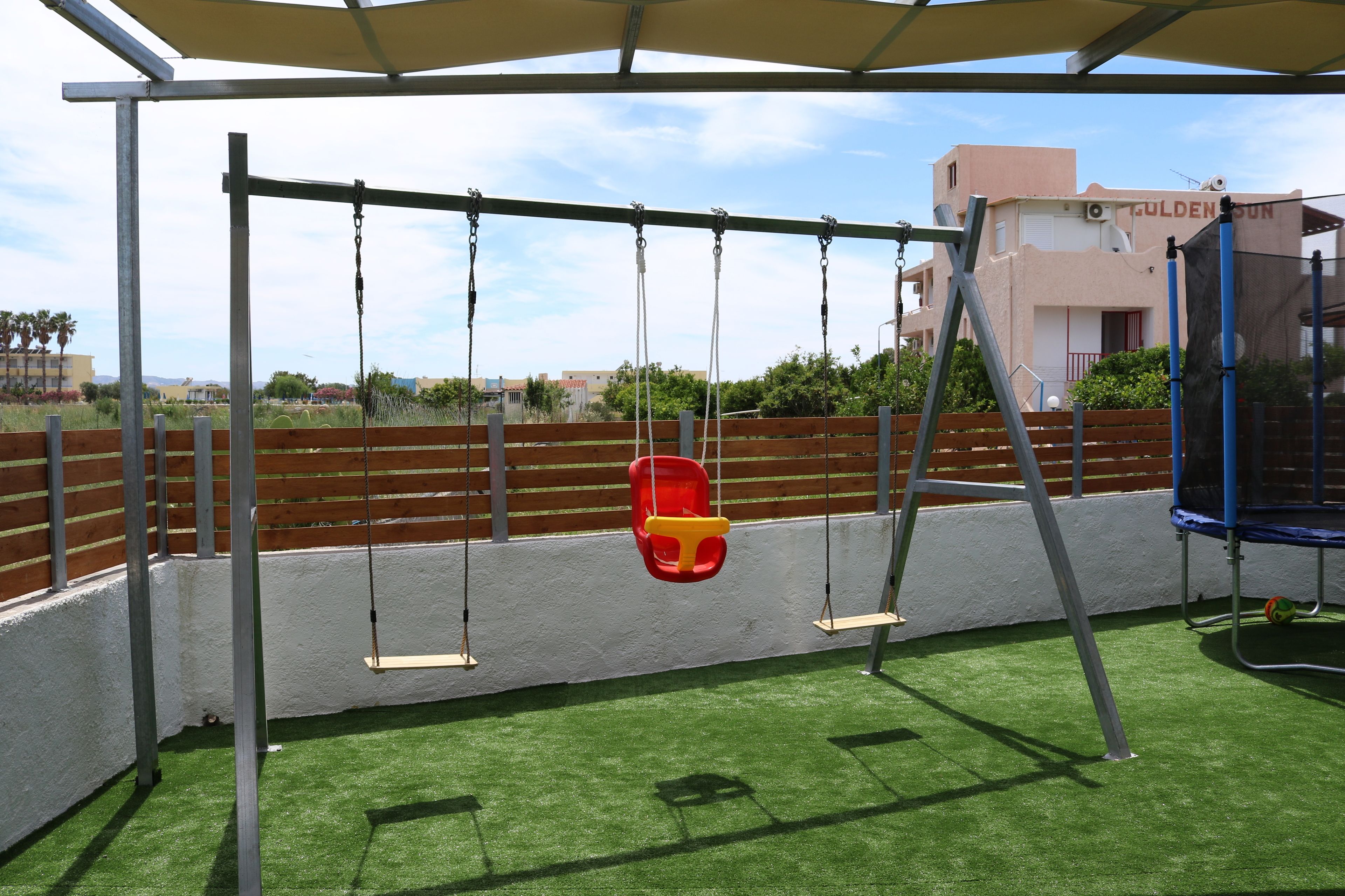 Ein Spielbereich im Freien mit Schaukeln und Trampolin.