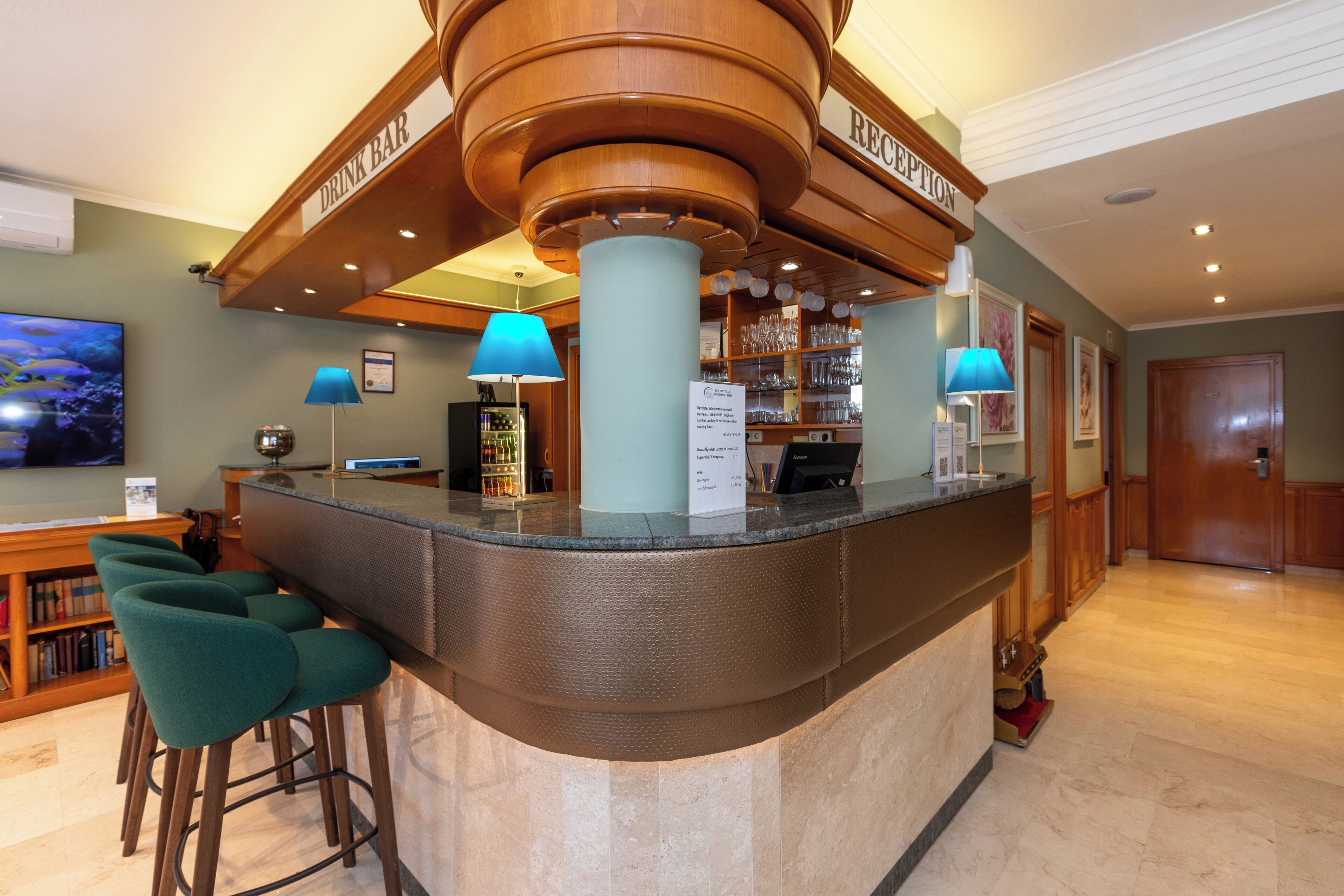 Un espace d’accueil comprenant un bar, des tabourets de bar, un téléviseur et un comptoir de réception.