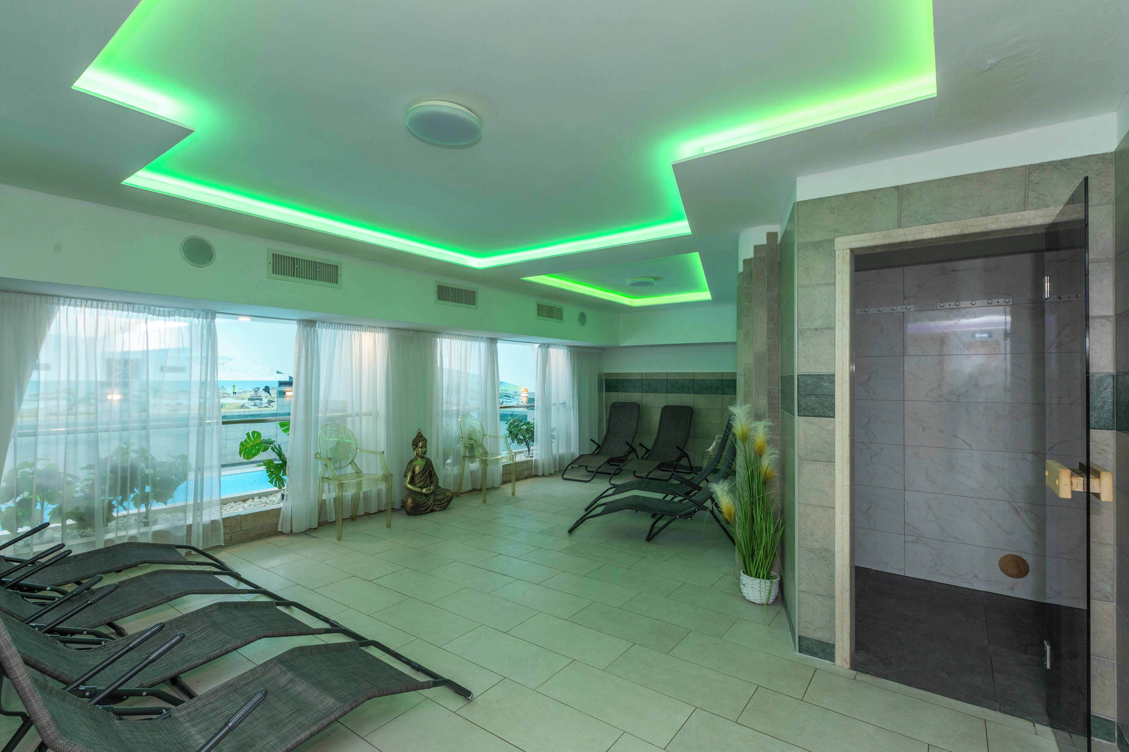A waiting area with a reception desk, seating, a Buddha statue, and a view of the outdoors.