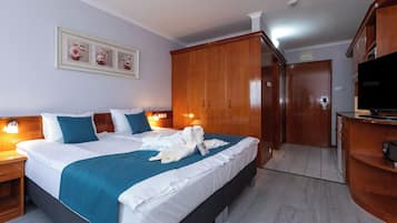 Quarto de hotel com uma cama grande, guarda-roupa de madeira, televisão e uma obra de arte emoldurada na parede.