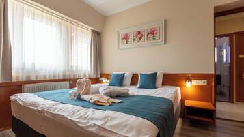 Hotelkamer met een groot bed, een nachtkastje, een wanddecoratie met bloemen en een raam met gordijnen.
