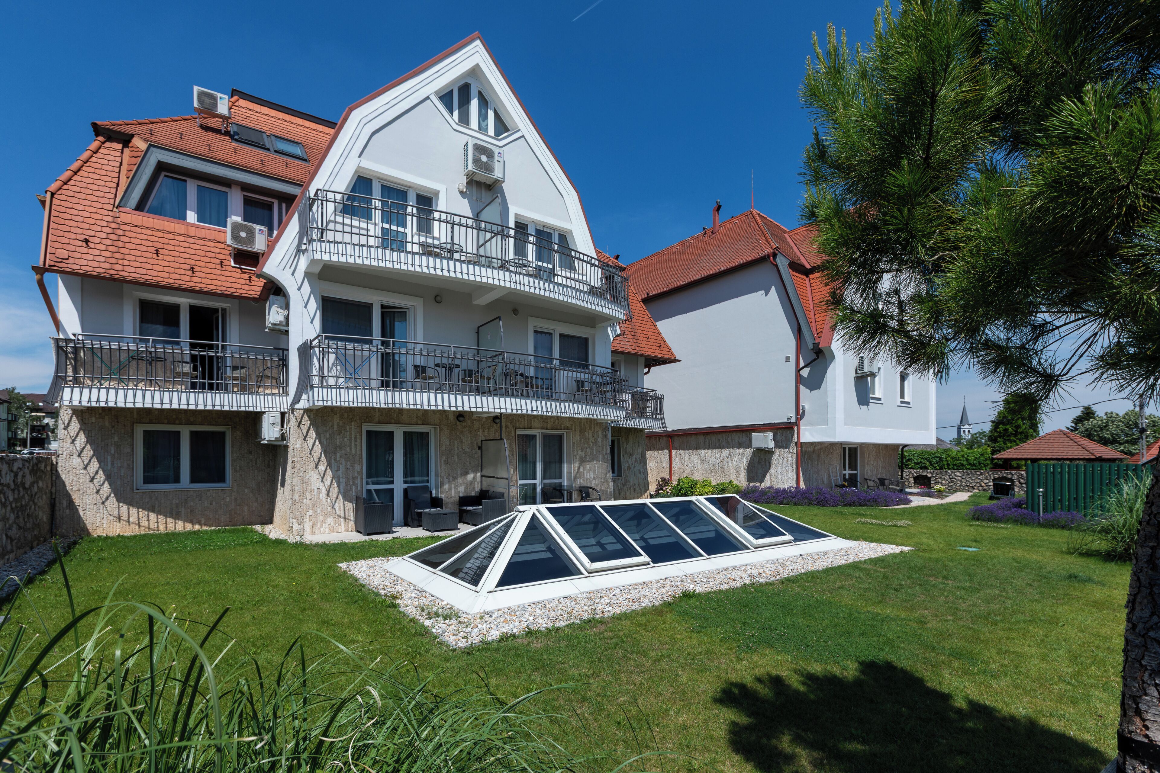 A two-story house with a sloped roof, a balcony, and a covered patio area.