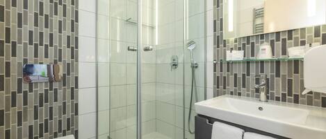 A modern bathroom with a glass-enclosed shower, a white sink, and a tiled backsplash.