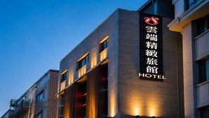 Un hôtel moderne, avec une enseigne bien visible en caractères chinois et le mot « HÔTEL » en anglais.