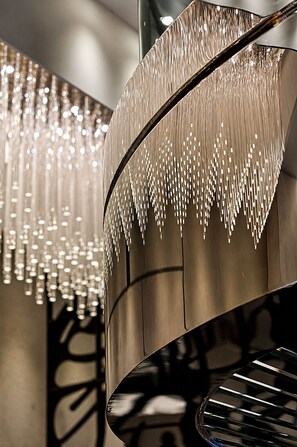 Un escalier en colimaçon avec une finition métallique et des luminaires suspendus.