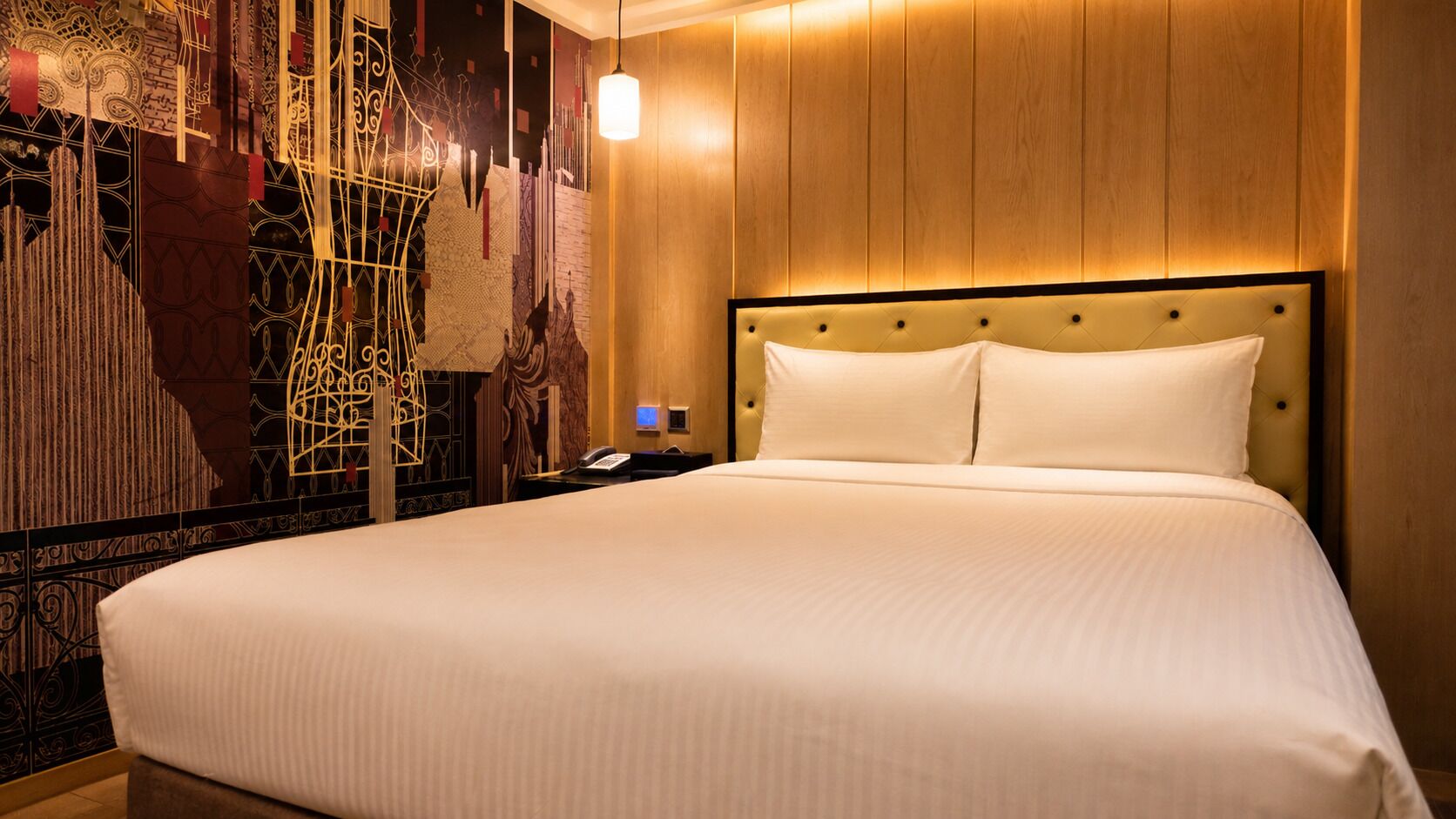 A hotel room with a large bed, a wooden headboard, and a wall with intricate designs.