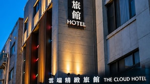 Un hôtel doté d’une enseigne bien visible, d’une entrée moderne et dont l’intérieur est clairement visible à travers les portes vitrées.