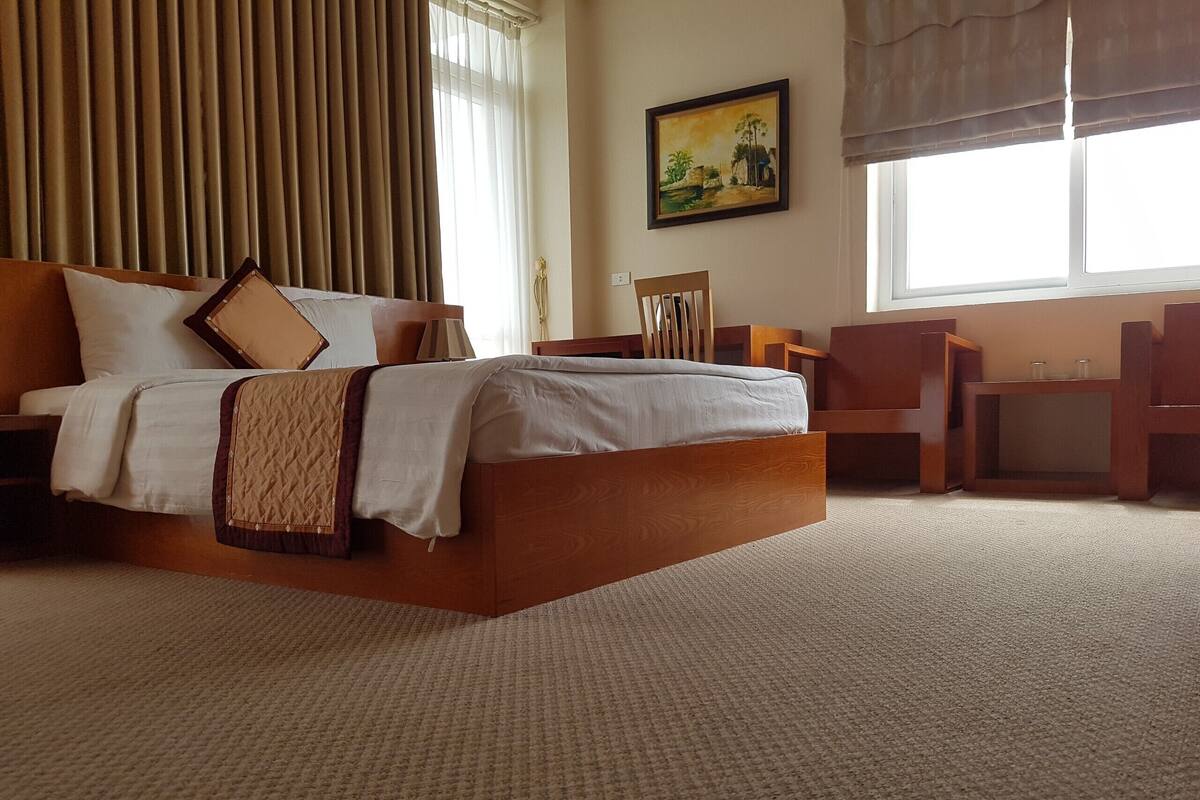 A hotel room with a large bed, a desk, and a chair.