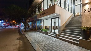 L’entrée d’un hôtel, avec un escalier menant à la porte, une enseigne indiquant « The Queen Hotel » et le chiffre « 20 » peint sur le mur.