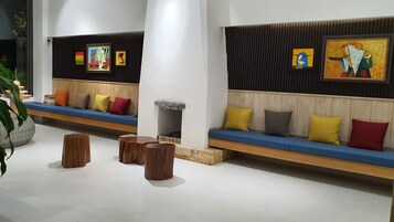 Un vestíbulo moderno con una amplia zona de asientos en un banco, detalles de madera y obras de arte en las paredes.