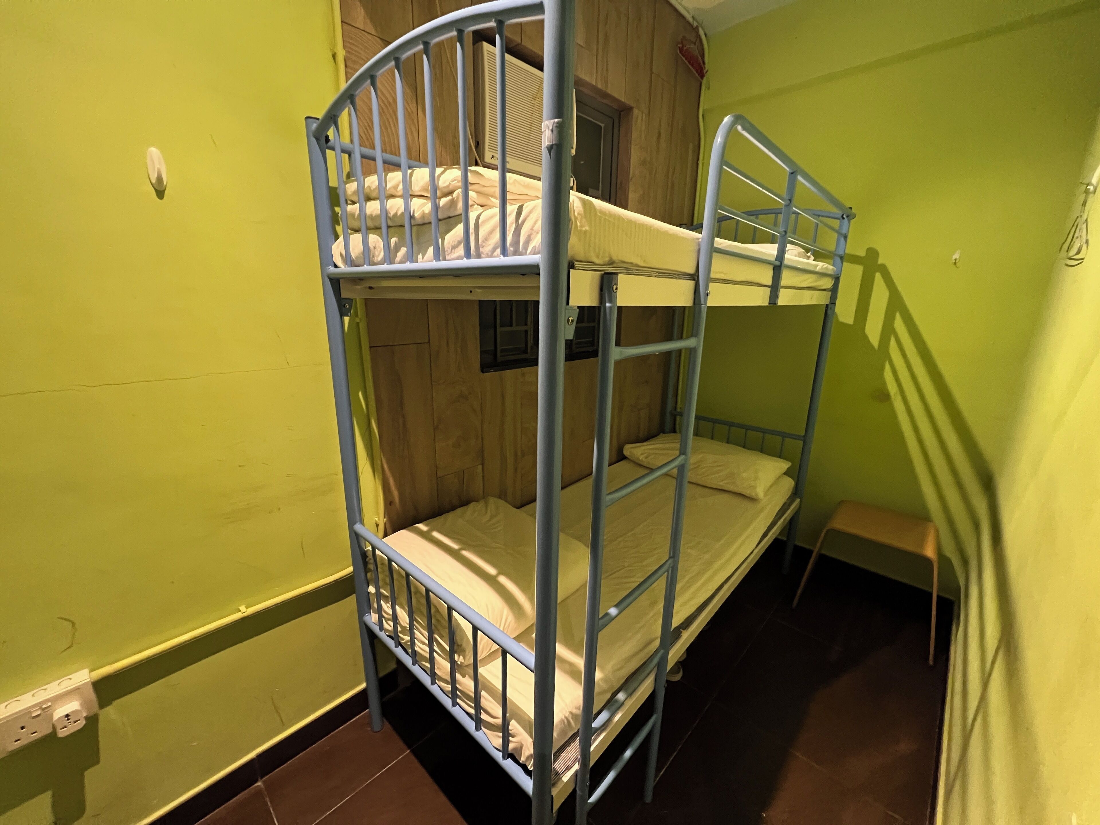 A bunk bed in a room with green walls and a wooden door.