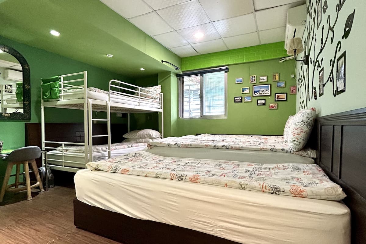 A dormitory room with bunk beds, a desk, and a chair.