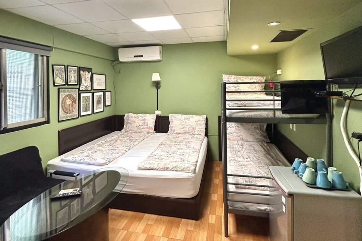 A room with two beds, a desk, a TV, and a window.