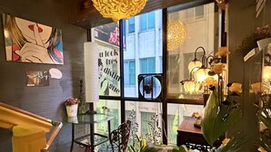 A cozy interior with a wooden staircase, a large hanging light fixture, and various potted plants. - Ximen Triple Tiger Hostel (Taipei)