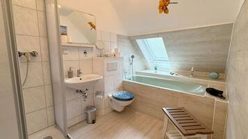 Une salle de bain moderne équipée d’une douche, d’un lavabo, de toilettes et d’un banc.