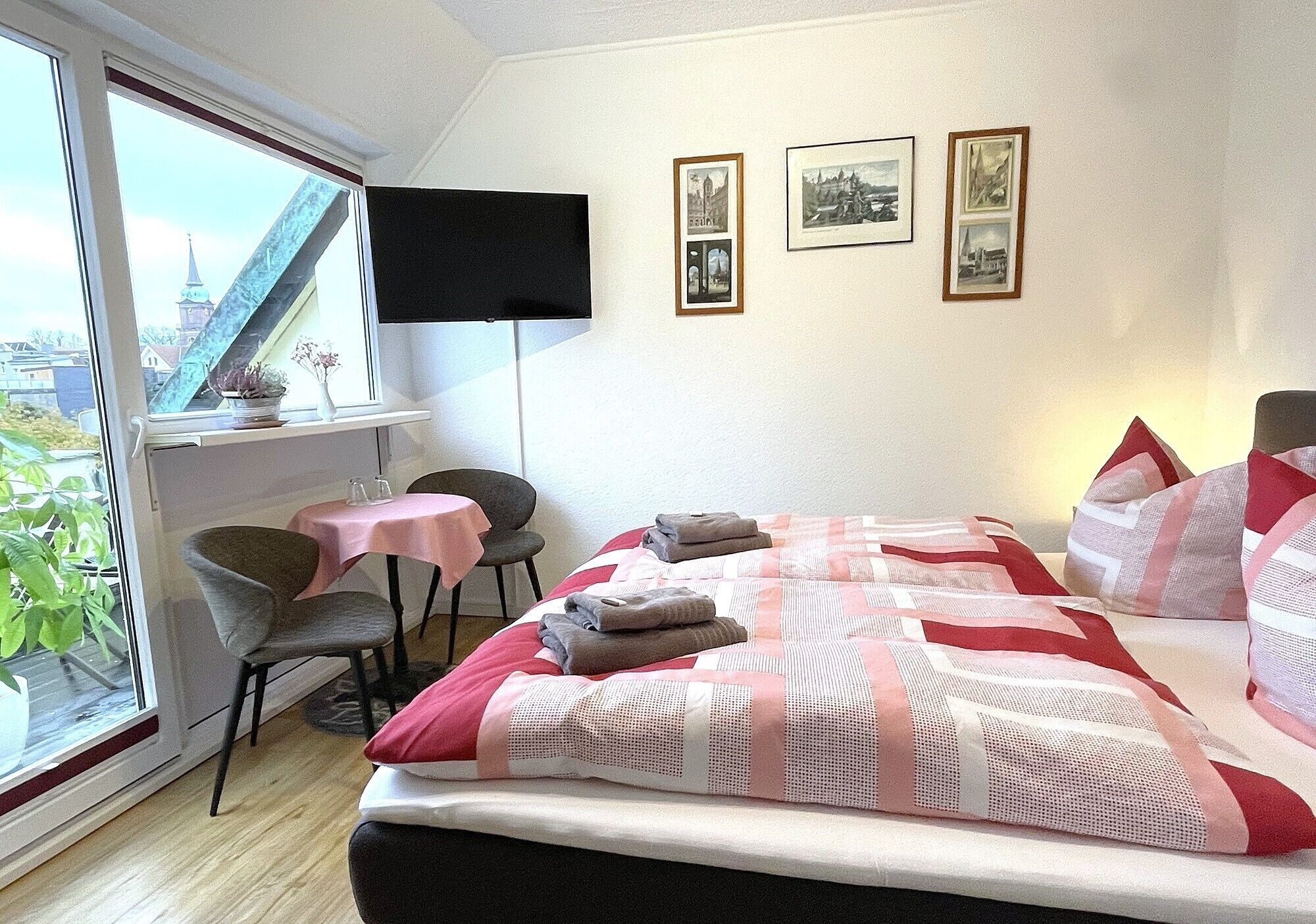 Habitación de hotel con cama, escritorio, silla y ventana con vista a un puente y edificios.