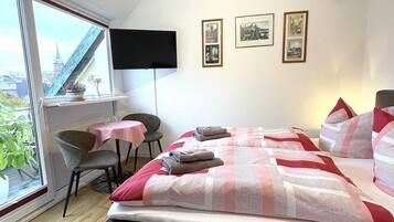Habitación de hotel con cama, escritorio, silla y ventana con vista a un puente y edificios.