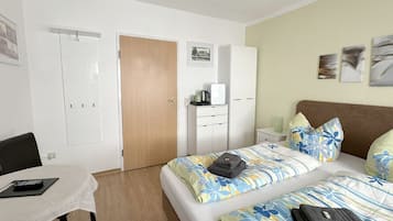 Habitació d'hotel amb dos llits, un escriptori, un armari i una cafetera.