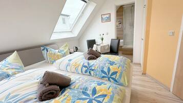 Een slaapkamer met dakraam, een bed met bloemenbedrijf, een nachtkastje met lamp, en een douchegedeelte.