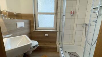A bathroom with a toilet, sink, and shower.