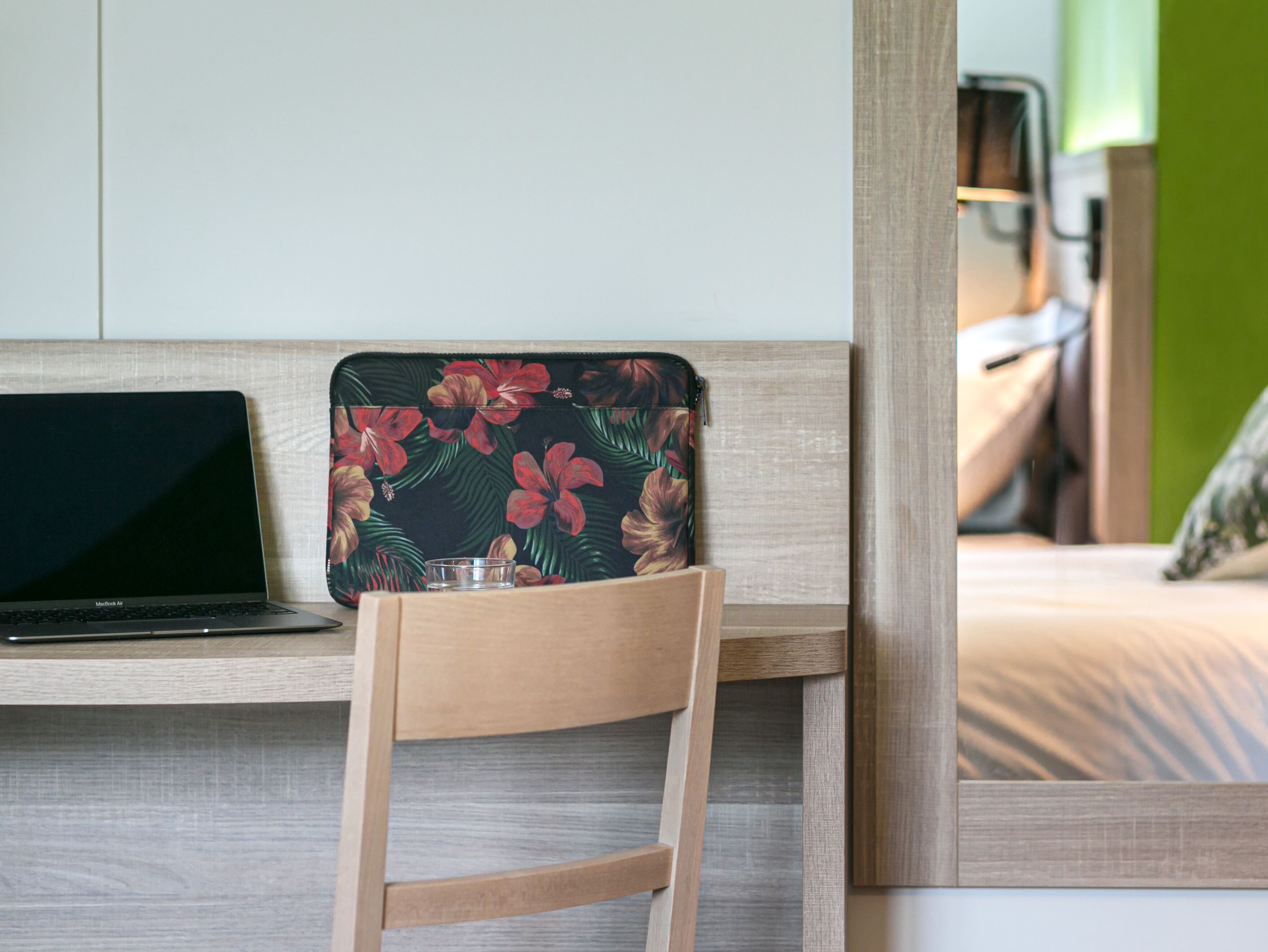Un escritorio de madera con una computadora portátil y un bolso estampado con motivos florales.
