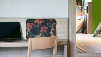 Un bureau en bois avec un ordinateur portable et un sac orné d’un motif floral.