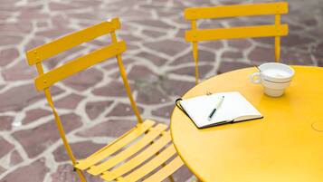 A yellow table with a white cup and a notebook with a pen on it.