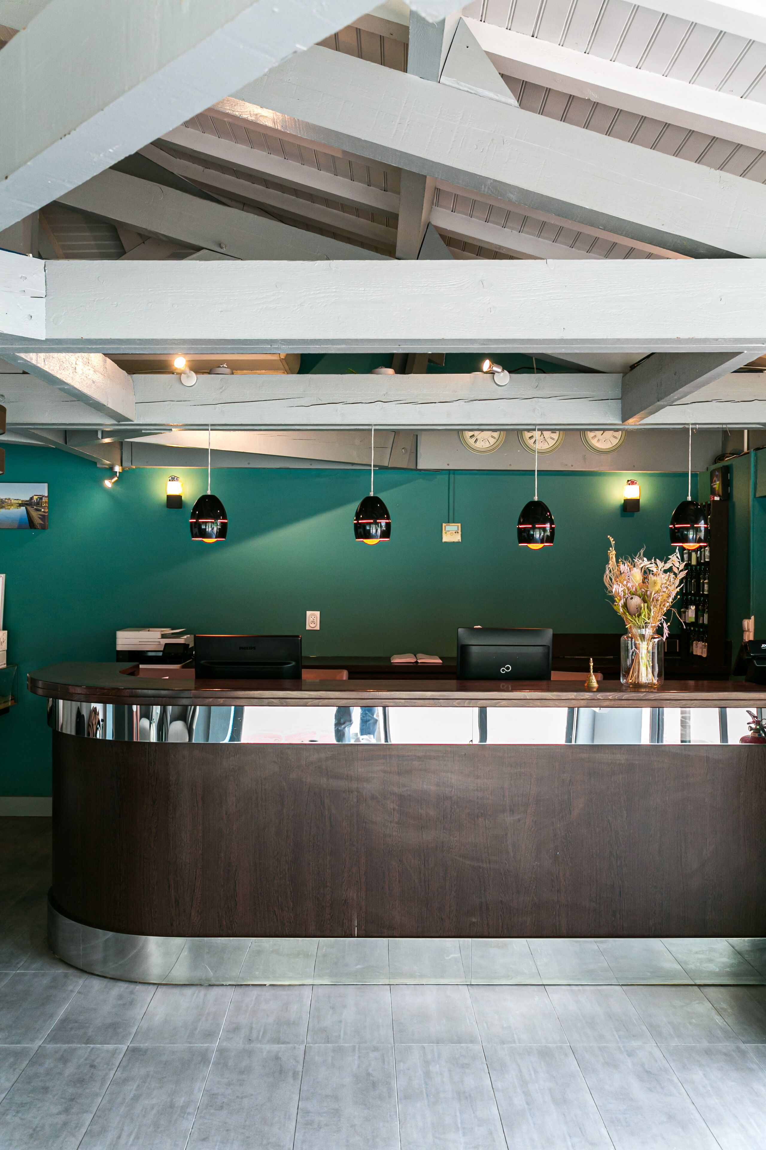 A reception area with a dark wooden counter, teal walls, and pendant lighting.