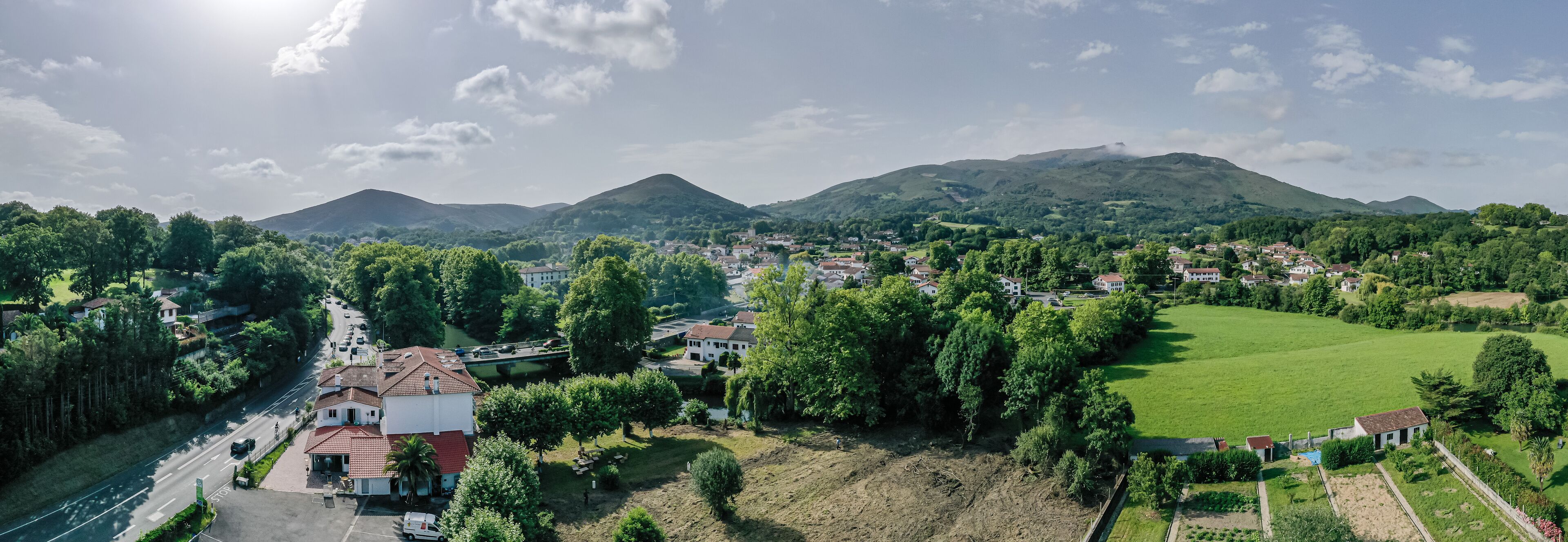 Une vue aérienne d’une ville avec une église imposante, un grand champ verdoyant et des collines douces en arrière-plan.