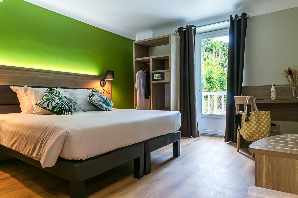A modern bedroom with a large bed, a walk-in closet, and a view of the outdoors.
