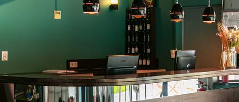 A modern reception area with a curved counter, pendant lighting, a clock, and a wine rack.