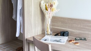 A wooden chair, a glass vase with dried flowers, a camera, a pair of glasses, and a magazine on a wooden table. - Hôtel du Pont d'Ascain (Ascain)