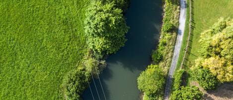 Vista aérea de un río bordeado por exuberante vegetación y un sendero pavimentado.