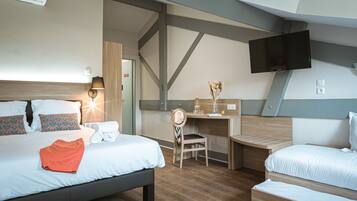 A hotel room with a large bed, a desk, a chair, and a TV mounted on the wall.