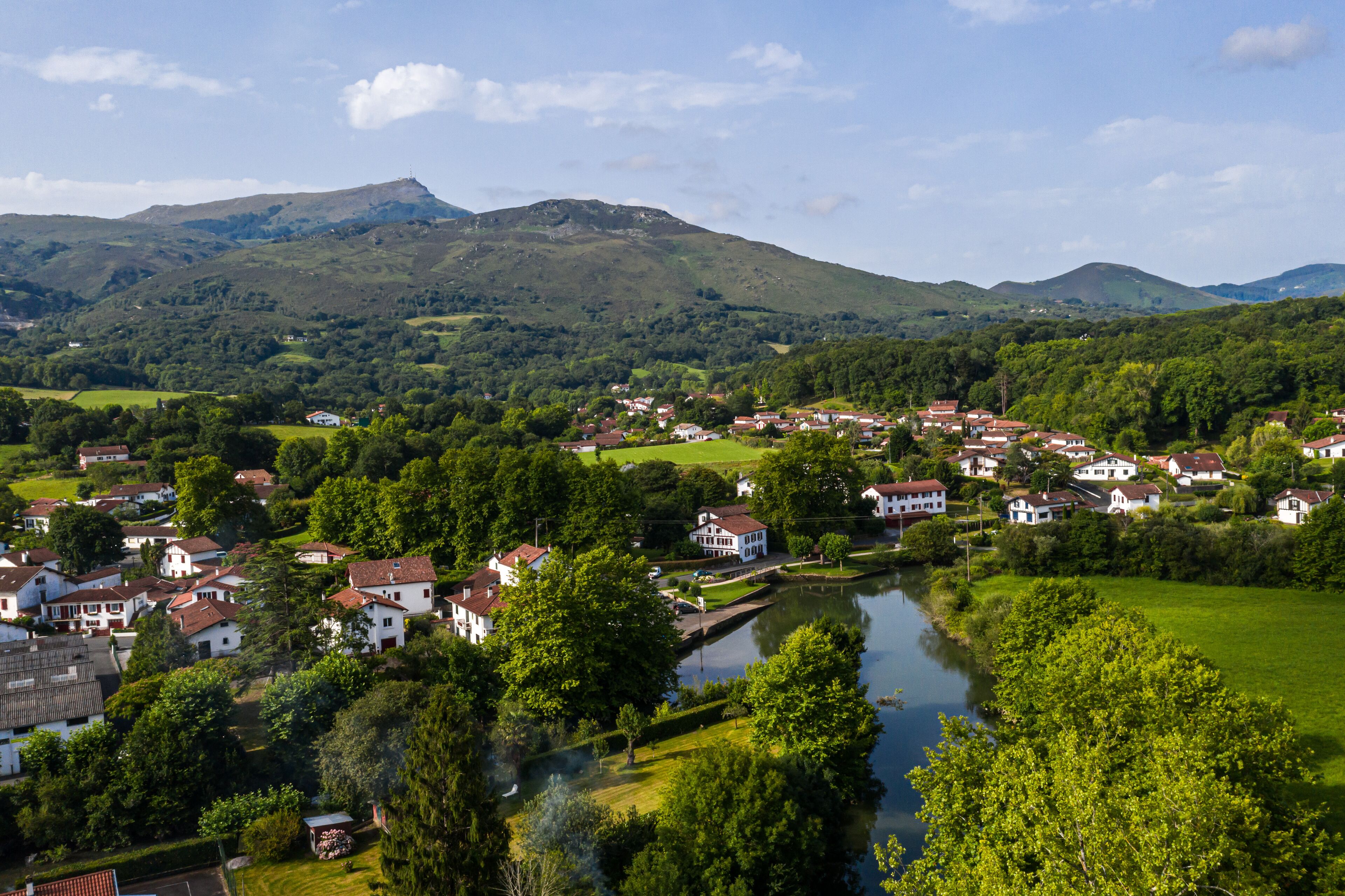 A riverside village with houses, a small canal, and hills in the background.