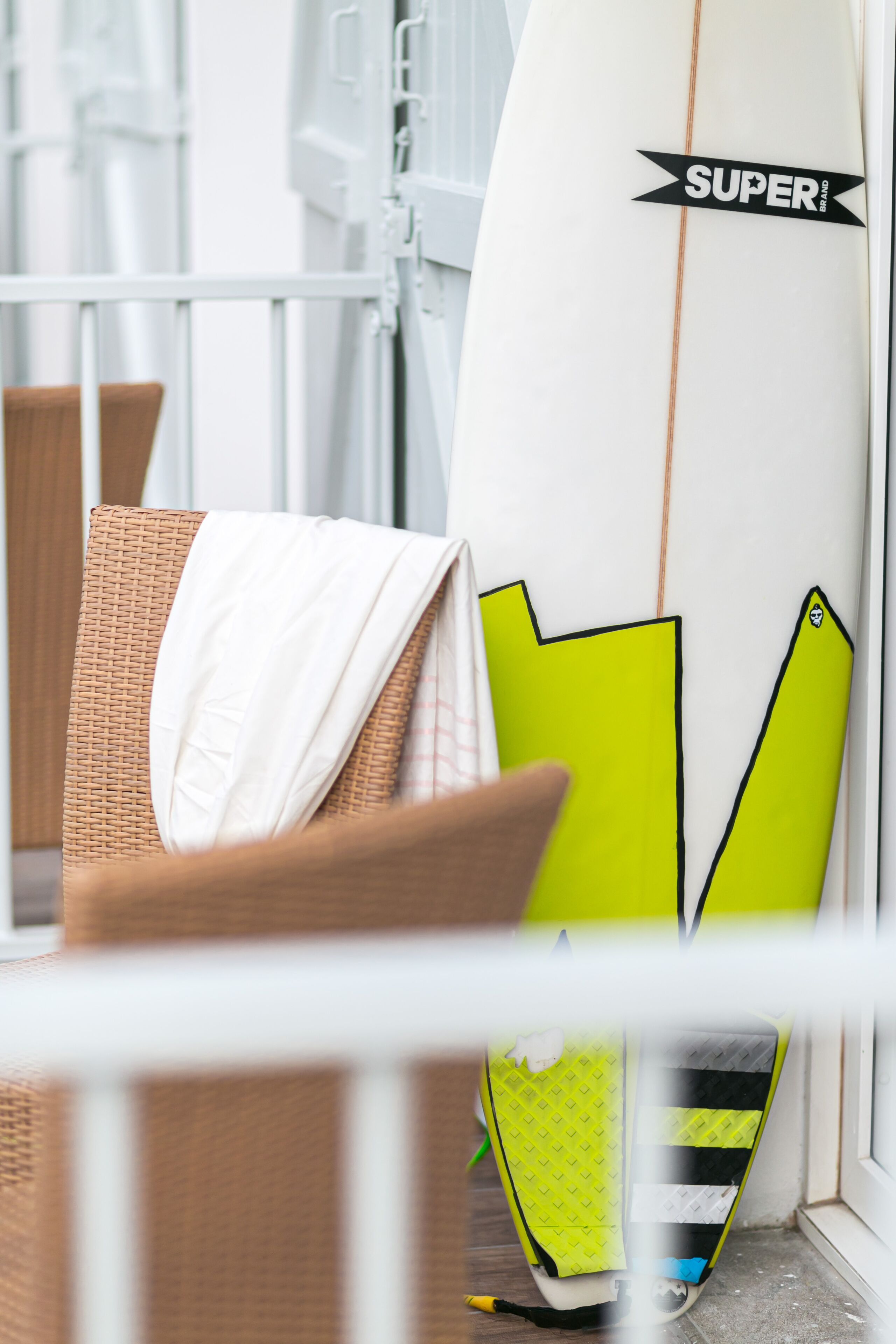 A white surfboard with a 'SUPER' logo leaning against a white railing.