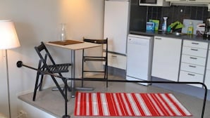 A compact kitchen with white cabinets, a microwave, and a dishwasher. There is a small dining area with a table and chairs. - Helsinki Apartment (Helsinki)