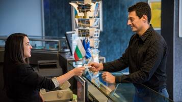 A person handing over a card to a cashier at a counter with a display of postcards behind them.
