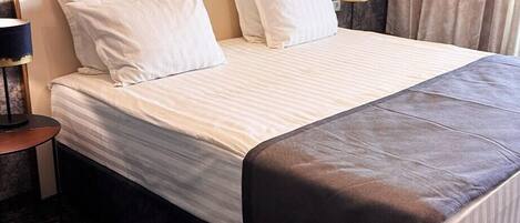 A hotel room with a large bed, two bedside tables, and a headboard with a geometric design.