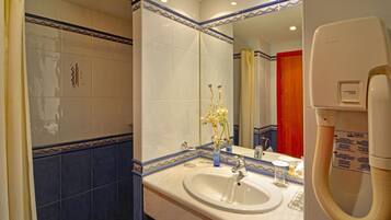 Un baño con lavamanos blanco, espejo y ducha.