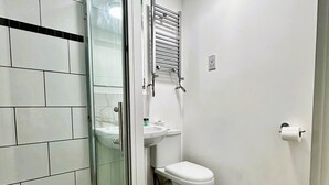 Ein Badezimmer mit Duschkabine, Toilette, Waschbecken und Handtuchhalter.