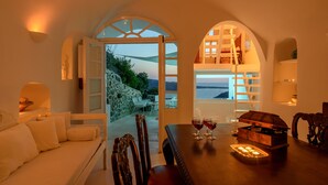 A dining area with a wooden table, chairs, and a view of the sea.