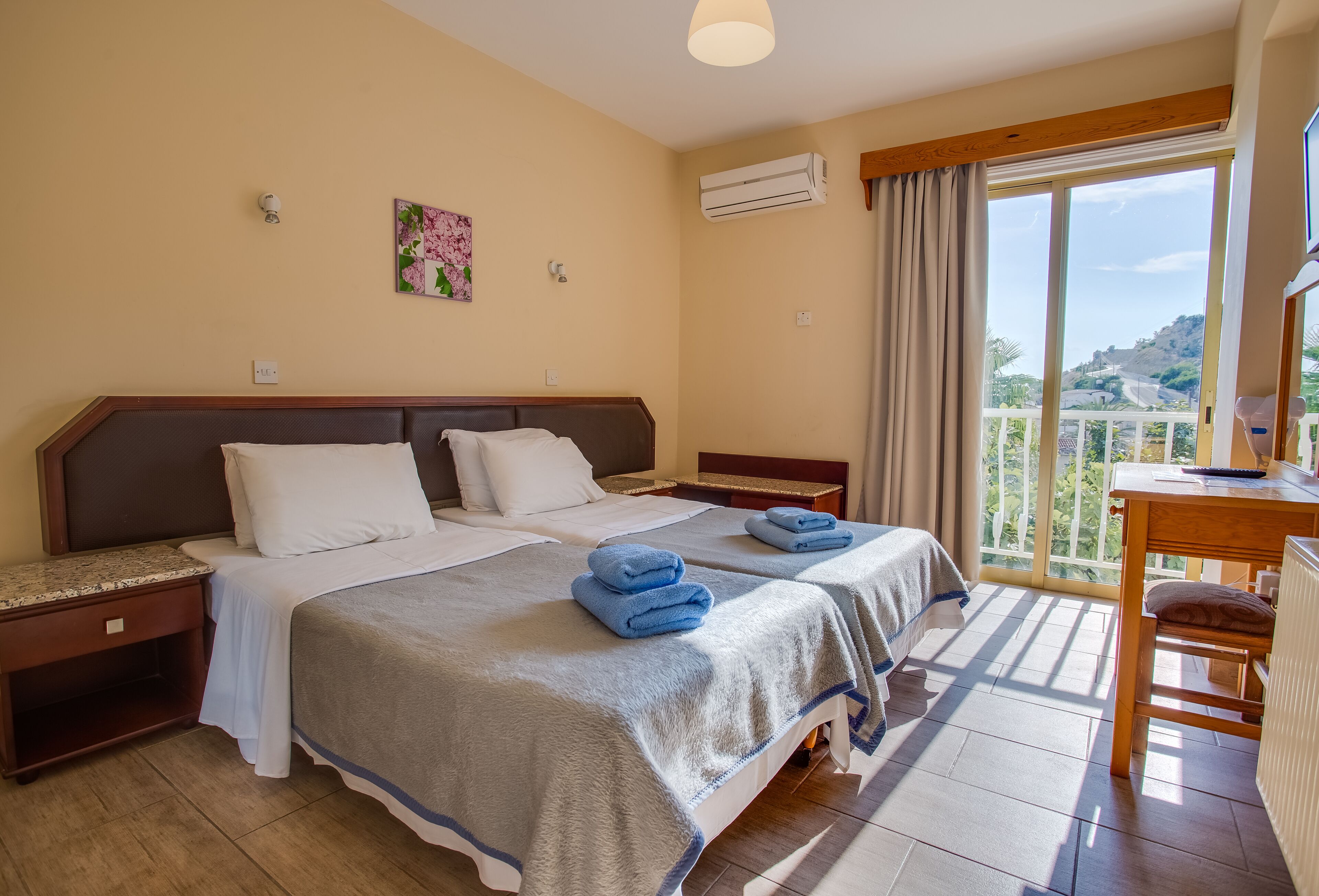 A hotel room with two beds, a balcony, and a view of the landscape.