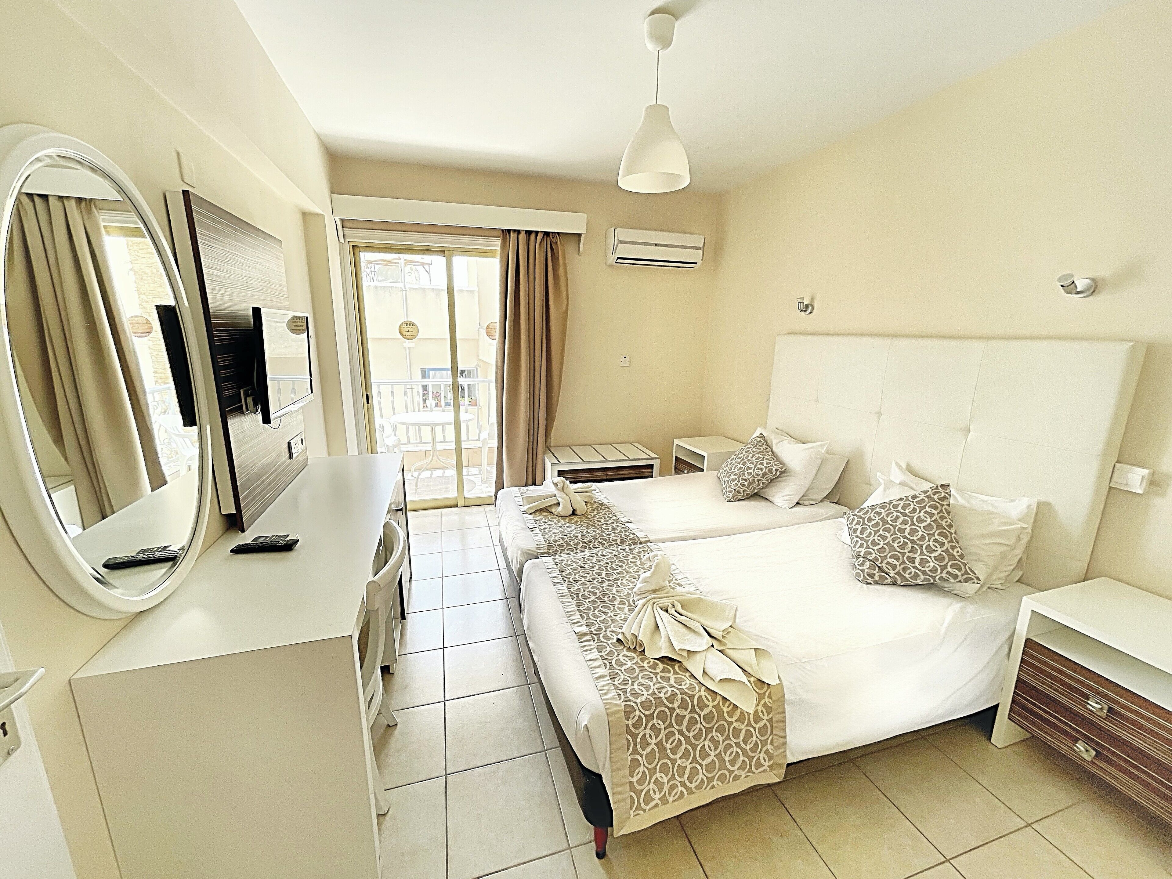 Une chambre d’hôtel équipée d’un lit, de tables de chevet, d’un bureau, d’un miroir et d’un appareil de climatisation.
