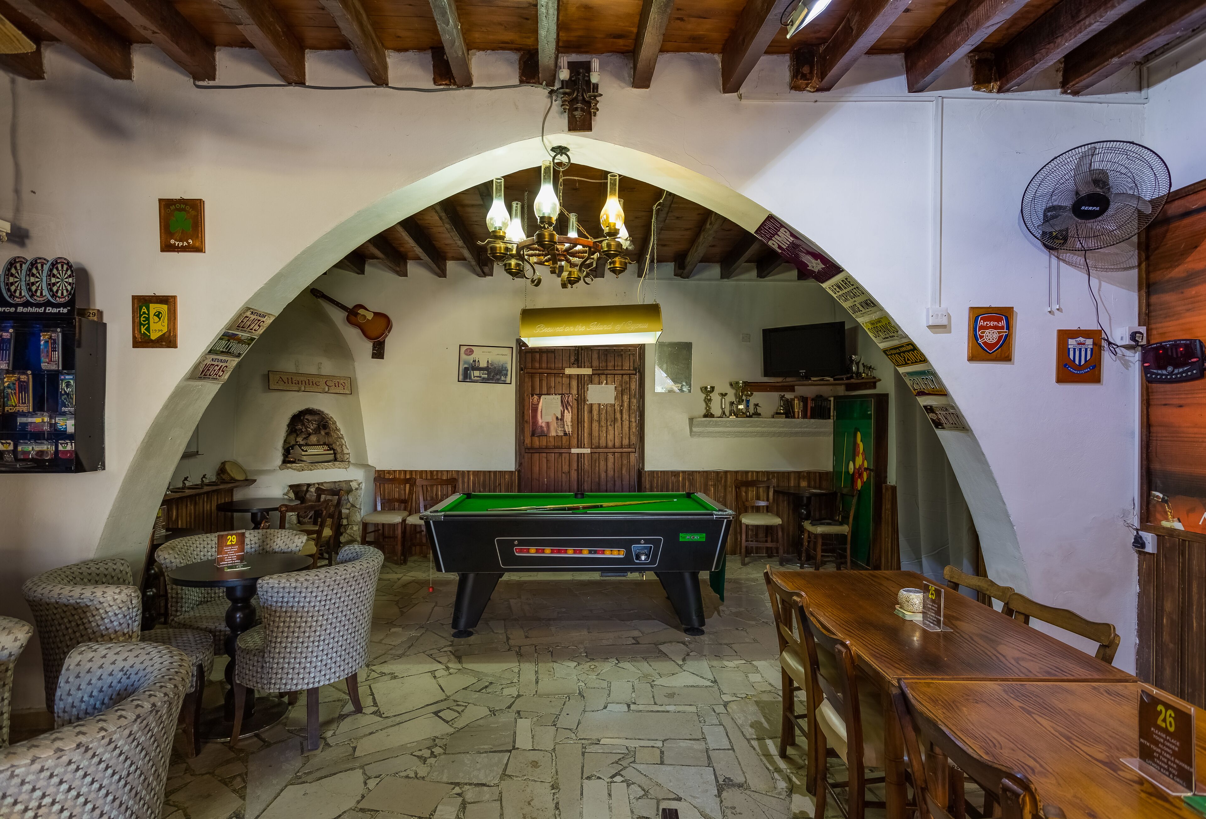 Una sala de billar con mesa de pool, sillas y un ventilador.