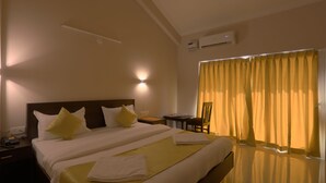Une chambre d’hôtel avec un grand lit, des tables de chevet, un bureau et une chaise.