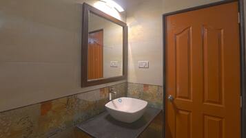 A bathroom with a white sink, a mirror, and a wooden door.