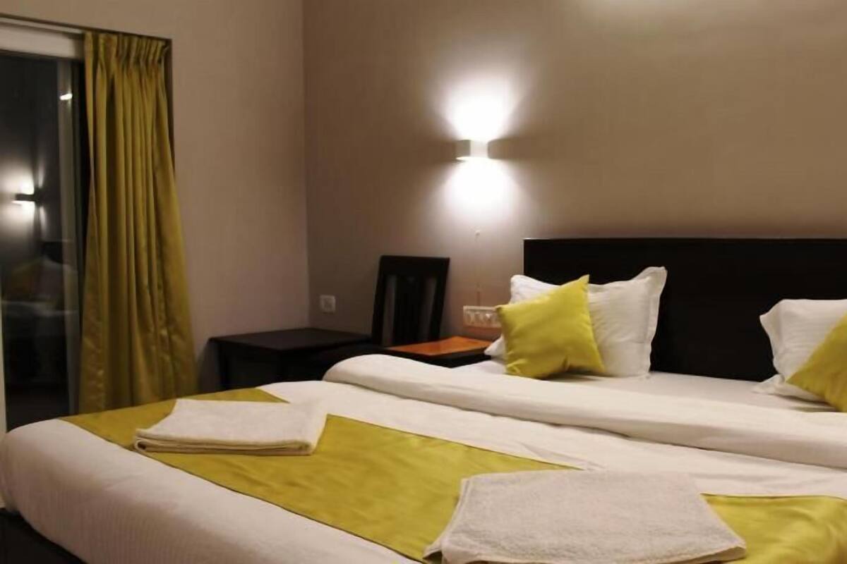 A hotel room with a bed, pillows, and a nightstand.