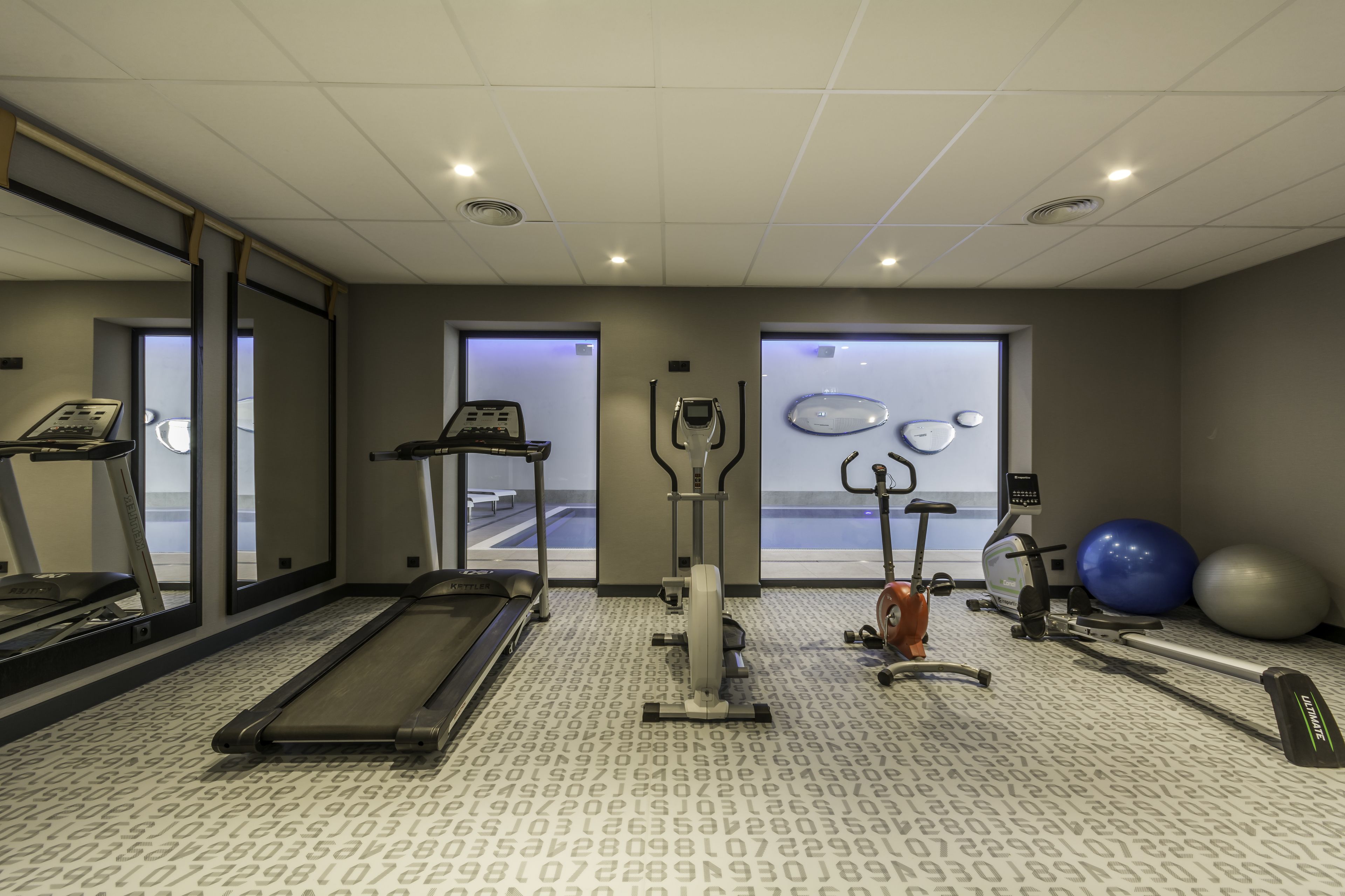 Une salle de sport équipée de tapis de course, de vélos elliptiques et de ballons d’exercice.